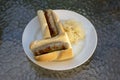 German sausages called bratwursts roasted in baguette with mustard, onion and pickled sauerkraut on white plate in Bosna style Royalty Free Stock Photo