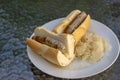 German sausages called bratwursts roasted in baguette with mustard, onion and pickled sauerkraut on white plate in Bosna style Royalty Free Stock Photo