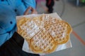 A german typical waffle in a hand with powdered sugar