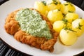 German veal schnitzel with boiled new potatoes and green sauce close-up in a plate. horizontal