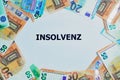 German word for insolvency printed on a white paper with Euro banknotes around