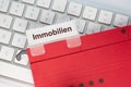 The German word for Real estate can be seen on the label of a red hanging folder. The hanging folder is on a computer keyboard Royalty Free Stock Photo