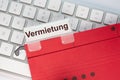 The German word for rental can be seen on the label of a red hanging folder. The hanging folder is on a computer keyboard