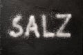 German word Salz meaning salt written with salt crystals on a dark slate, high angle view from above Royalty Free Stock Photo