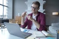 German young male entrepreneur in glasses having pleasant online conversation with colleagues