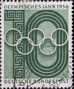 GERMANY - CIRCA 1956: aThis postage stamp in green shows the Olympic rings against the background of a stylized sports arena and m