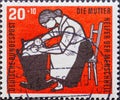 GERMANY - CIRCA 1956: a charitably postage stamp printed in Germany showing a mother who mothers your child in the cradle as a hel