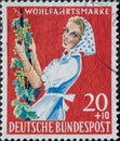 GERMANY - CIRCA 1958: a charitably postage stamp printed in Germany showing a winemaker with apron and headscarf harvesting wine