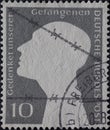 GERMANY - CIRCA 1953: this postage stamp, printed in germany, shows the silhouette of a white head behind barbed wire. The gray ba