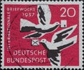 GERMANY - CIRCA 1957: This postage stamp shows two white carrier pigeons with letters in their beaks against a red background. Tex Royalty Free Stock Photo