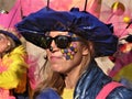 Participant in very colorful costumes and hat , made of shiny fabric. Funny painted female face