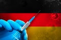 Germany Covid-19 Vaccination Campaign. Hand in a blue rubber glove holds a syringe with covid-19 virus vaccine in front of Germany Royalty Free Stock Photo