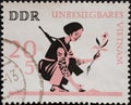 GERMANY, DDR - CIRCA 1966 : a postage stamp from Germany, GDR showing an armed Asian girl with a rifle on her back is planting a