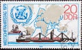 GERMANY, DDR - CIRCA 1979 : a postage stamp from Germany, GDR showing the container ship `Meridian`, tug, emblem of the IMC. Wor Royalty Free Stock Photo