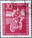 GERMANY, DDR - CIRCA 1959 : a postage stamp from Germany, GDR showing a mail delivery woman with a moped with houses. Postage Stam