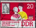 GERMANY, DDR - CIRCA 1964 : a postage stamp from Germany, GDR showing a woman helps child with schoolwork, picture by Jenny Marx.