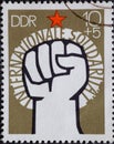 GERMANY, DDR - CIRCA 1975 : a postage stamp from Germany, GDR showinga raised fist, red star. International solidarity