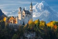 Germany. Famous Neuschwanstein Castle in the background of snowy mountains and trees with yellow and green leaves. Royalty Free Stock Photo