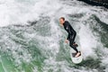 Germany, Munich - September 01, 2013. Atractive sporty man in neoprene shorty surfing on famous artificial river wave