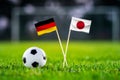 Germany vs. Japan, Khalifa Stadium, Football match wallpaper, Handmade national flags and soccer ball on green grass. Football Royalty Free Stock Photo