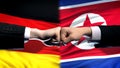 Germany vs North Korea conflict, fists on flag background, diplomatic crisis Royalty Free Stock Photo