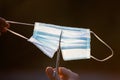 Close up of scissors while cutting a surgical mask. End of coronavirus pandemic