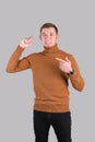 The gesture is small in size. A red-bearded hipster man in a red sweater shows a small size gesture and points at him with his Royalty Free Stock Photo