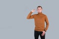 The gesture is small in size. A red-bearded hipster man in a red sweater shows a small size gesture standing on a gray background Royalty Free Stock Photo
