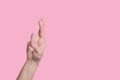 Gesture symbol of good luck, fingers crossed, bright hand on a pink background.