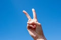 Gesture symbol number two. Two fingers of a caucasian woman hand showing victory or peace gesture on blue sky Royalty Free Stock Photo