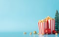 Side view of striped popcorn boxes, ornaments, and a mini Christmas tree against a blue wall for film promotions