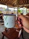 old fashioned enamel cup in white with green prints held in hand