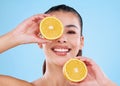 Get a dose of citrus. Studio portrait of an attractive young woman posing with two halves of an orange against a blue Royalty Free Stock Photo