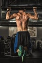 Muscular male athlete doing pull-ups on horizontal bar at the gym