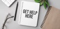 get help here is written in a white notebook with calculator, craft colored notepad, plant, black marker and glasses Royalty Free Stock Photo