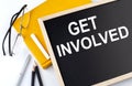 GET INVOLVED text on the blackboard with notepad , pen, pencil Royalty Free Stock Photo