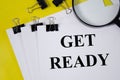 Get ready concept word written on white paper and yellow background with magnifier. text