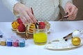 Get ready for Easter, paint eggs. Hands make colorful handmade jewelry, top view on a light background