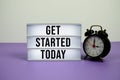 Get Started Today text on LED lightbox with alarm clock on purple background Royalty Free Stock Photo