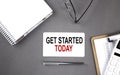 GET STARTED TODAY text written on the card with notebook and clipboard, grey background