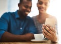 The get to know you part of the date. Shot of a young man and woman using a mobile phone together on a date at a coffee Royalty Free Stock Photo