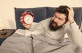 Get up with alarm clock. Overslept again. Tips for waking up early. Man bearded sleepy face bed with alarm clock in bed