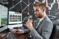 Get your financial power. Portrait of successful trader looking aside and drinking coffee while sitting in front of Royalty Free Stock Photo