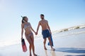 Getaway for a great vacation. a young couple walking along a beach together with snorkeling gear. Royalty Free Stock Photo