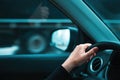 Getting away from it all concept, closeup of female hand on car steering wheel, woman driving vehicle along the road and passing