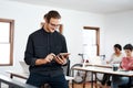 Getting business done, one task at a time. a handsome young businessman using a tablet while his colleagues work behind Royalty Free Stock Photo