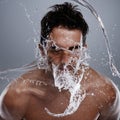 Getting clean. Studio shot of a young man with water splashing on his face. Royalty Free Stock Photo