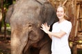 Getting close - Thailand. Portrait of a young eco-tourist gently petting a young Asian elephant.