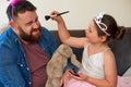 Getting Dad all dolled up. an adorable little girl putting makeup on her father at home. Royalty Free Stock Photo