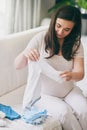 Getting everything ready before the baby comes. a pregnant woman sorting baby clothes.